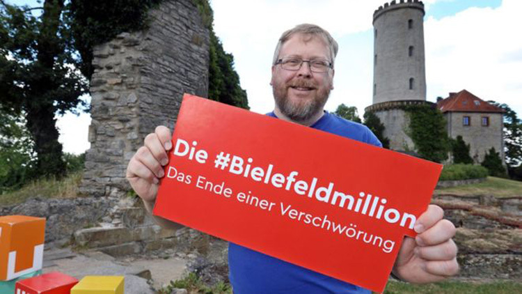 Achim Held giơ biển ủng hộ cuộc thi Bielefeld không tồn tại. Ảnh: BBC.