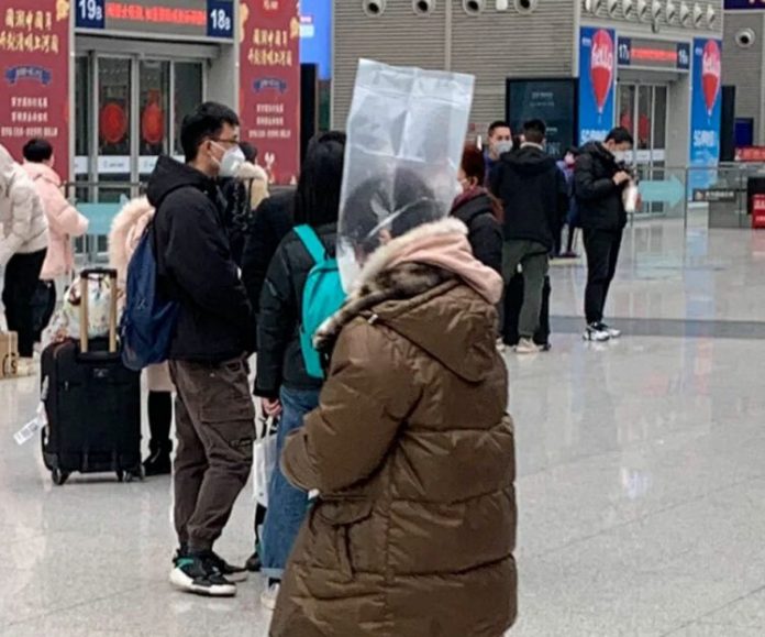 Một người phụ nữ đội túi giấy bóng lên đầu. Tại Trung Quốc, hành khách sẽ bị cấm sử dụng phương tiện giao thông công cộng nếu họ không đeo khẩu trang.