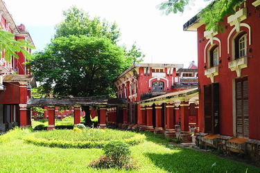 Khoảng đất trống giữa các khu nhà được phủ xanh bởi thảm cỏ và cây cao, tạo không gian dịu mát trong ngôi trường màu đỏ. Ảnh: Nguyễn Hoàng Hà