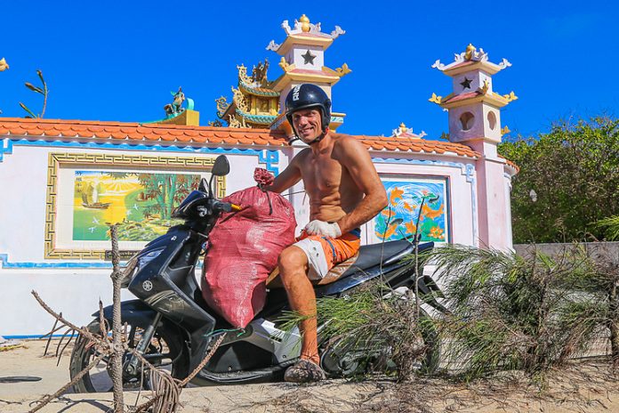 Vận động viên lướt sóng Nga Igor Yudakov tự lái xe máy để vận chuyển các bao rác. Ảnh: Maria Nelasova