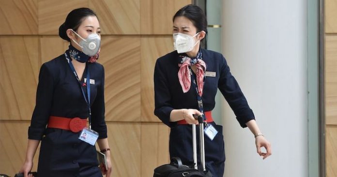 Tiếp viên hàng không đeo khẩu trang để ngăn ngừa nguy cơ nhiễm virus corona khi làm việc. Ảnh: En24.