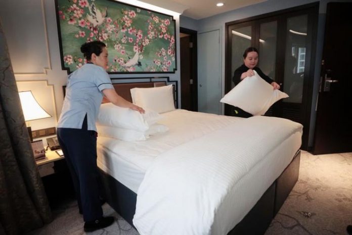 Dọn phòng của khách sạn Copthorne King, Vicky Zhang (trái), và Rachel Chen, trợ lý giám đốc điều hành, trình diễn cách họ dọn giường. Ảnh: Jason Quah/ Straitstimes.