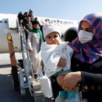 Hàng không đồng loạt hủy chuyến đến Iran Hành khách đeo khẩu trang rời khỏi máy bay khi đến sân bay Najaf, Iraq. Ảnh: Alaa al-Mar/Reuters.