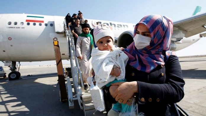 Hành khách đeo khẩu trang rời khỏi máy bay khi đến sân bay Najaf, Iraq. Ảnh: Alaa al-Mar/Reuters.