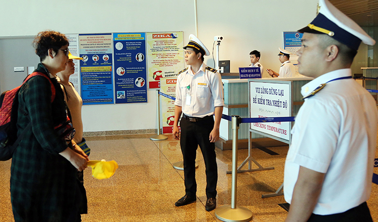 Nhân viên y tế của Trung tâm Kiểm dịch y tế quốc tế theo dõi thân nhiệt khách Trung Quốc qua máy tín