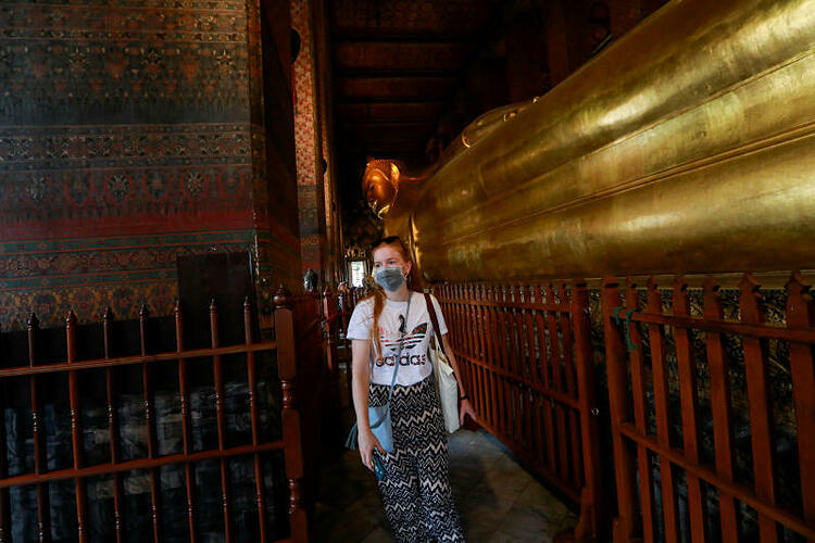 Một du khách nước ngoài mang khẩu trang khi tham quan chùa Wat Pho, Bangkok. Ảnh: Reuters.