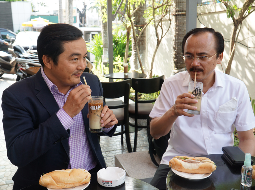 Ông Bùi Tá Hoàng Vũ (trái) và ông ông Võ Quốc Thắng - một trong ba thành viên sáng lập chuỗi cà phê Ông Bầu (phải) - đang thưởng thức cà phê và bánh mì tại chi nhánh cà Phê Ông Bầu, sáng 24/3.