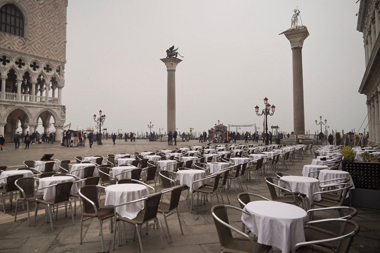 Bàn ghế của nhà hàng trống không trên Quảng trường Thánh Mark ở Venice. Vốn là một trong những thành phố điển hình cho tình trạng quá tải du lịch, Venice nay trống không. Điều khiến thành phố kênh đào này khác biệt với những điểm du lịch khác như Rome và Milan, là người dân gần như không có nguồn thu nhập nào khác ngoài du lịch. Ảnh: Renata Brito/AP.